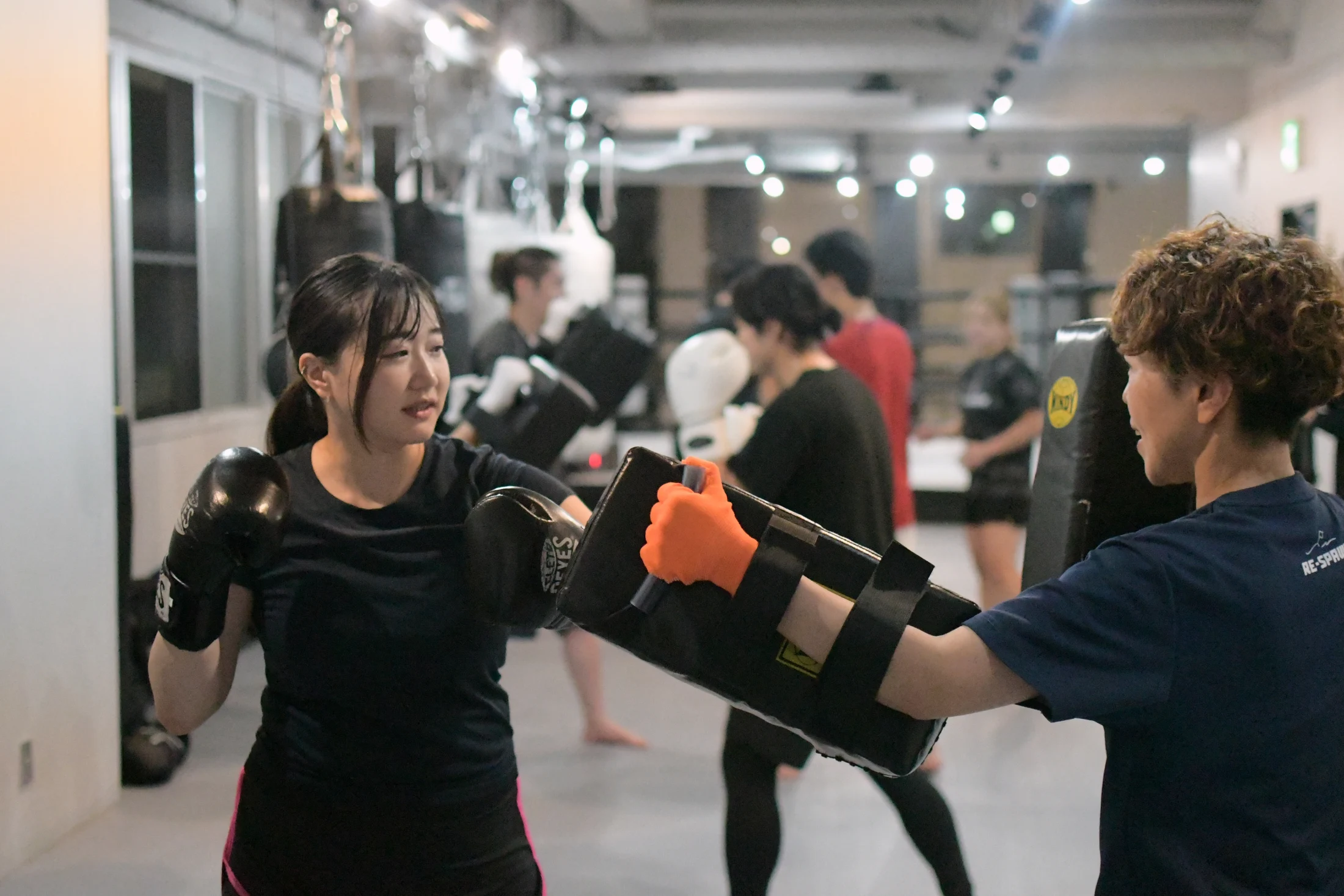 トレーナーとミット打ちに取り組む女性
